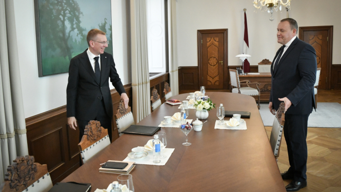 Valsts prezidents un iekšlietu ministrs sēžas pie galda