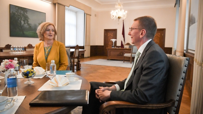 Ilze Indriksone un Edgars Rinkēvičs sēž pie galda un sarunājas