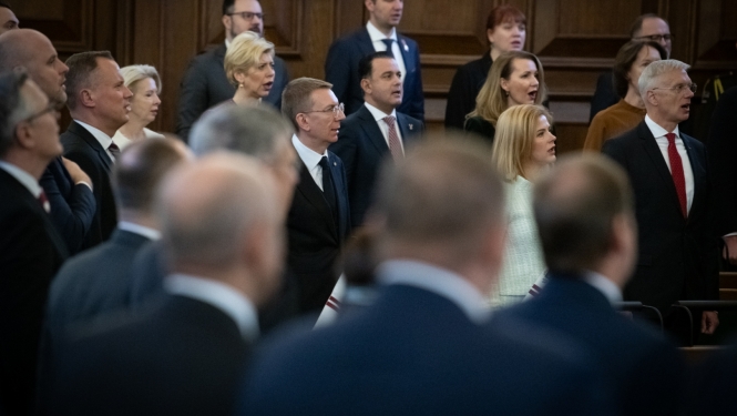 Svinīgās Saeimas sēdes dalībnieki stāv kājās un dzied Latvijas valsts himnu
