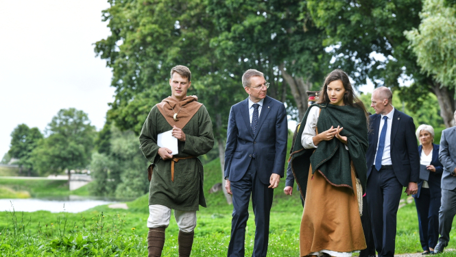 Valsts prezidents pastaigājas pa Grobiņas viduslaiku pils parku kopā ar pils darbiniekiem, kuri ģērbti vēsturiskos tērpos