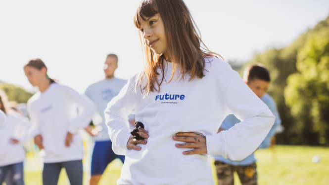 Bērni pļavā baltos džemperos ar uzrakstu Future