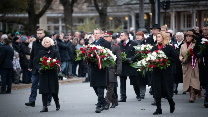 Amatpersonas iet ar ziedu vainagiem rokās
