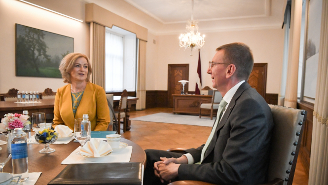 Ilze Indriksone un Edgars Rinkēvičs sēž pie galda un sarunājas