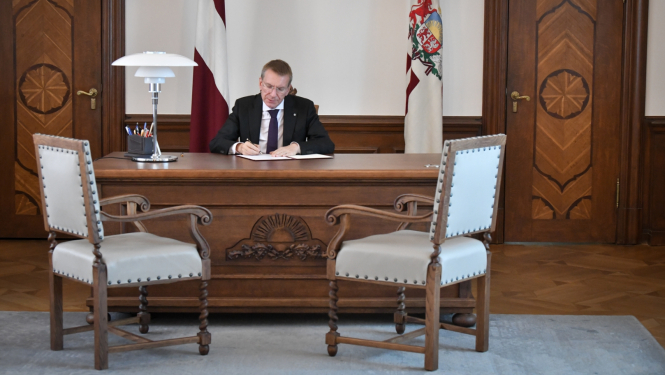 Edgars Rinkēvičs sēž kabinetā pie galda un paraksta dokumentus