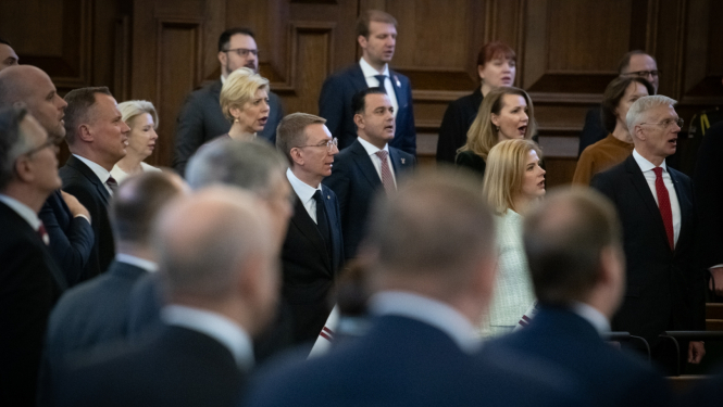 Svinīgās Saeimas sēdes dalībnieki stāv kājās un dzied Latvijas valsts himnu