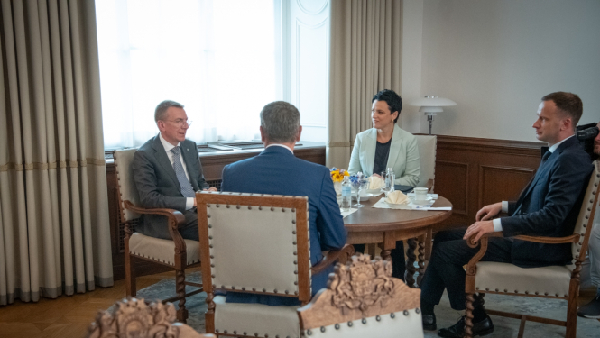 No kreisās: Edgars Rinkēvičs, Gunda Reire, Mārtiņš Drēģeris, Māris Sprindžuks (ar muguru) sēž ap galdu un sarunājas