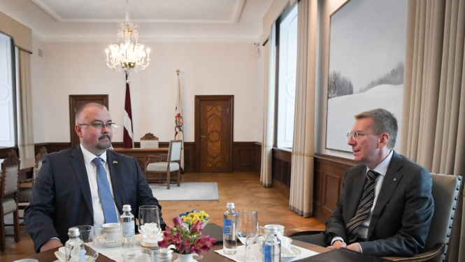 Jēkabs Straume un Edgars Rinkēvičs sēž pie galda un sarunājas