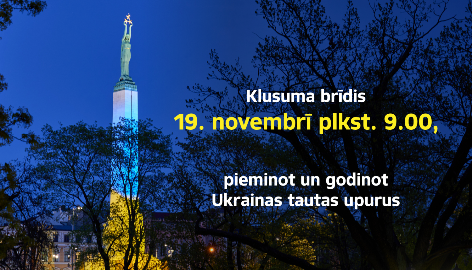 Vizuālis, kas informē par aicinājumu klusuma brīdim 19.novembrī plkst. 9.00, pieminot un godinot Ukrainas tautas upurus. Fona izgaismots Brīvības piemineklis Ukrainas karoga krāsās