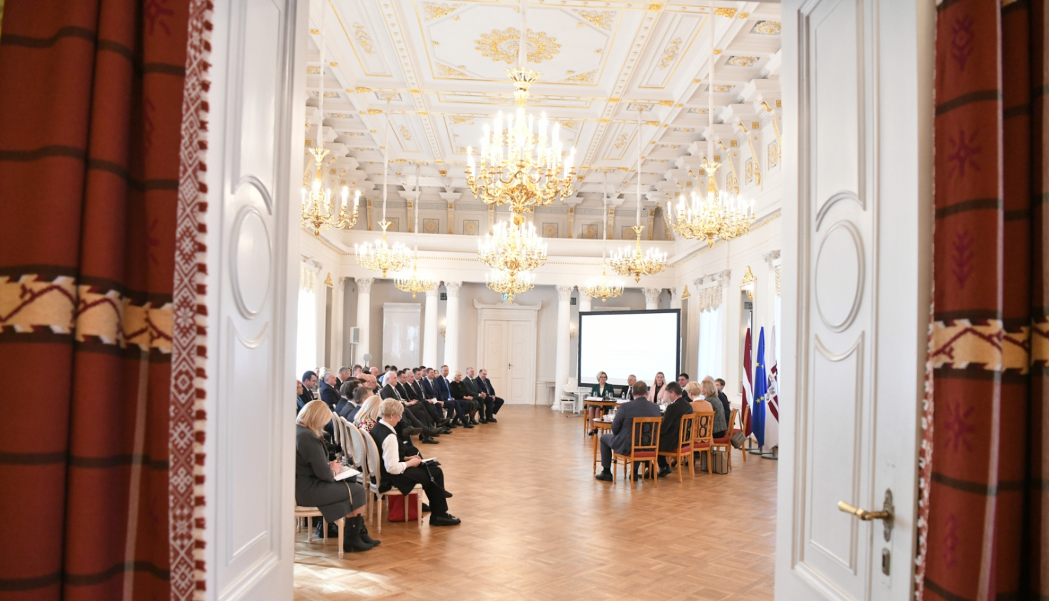 Skats caur atvērtām durvīm uz sarunas dalībniekiem zālē