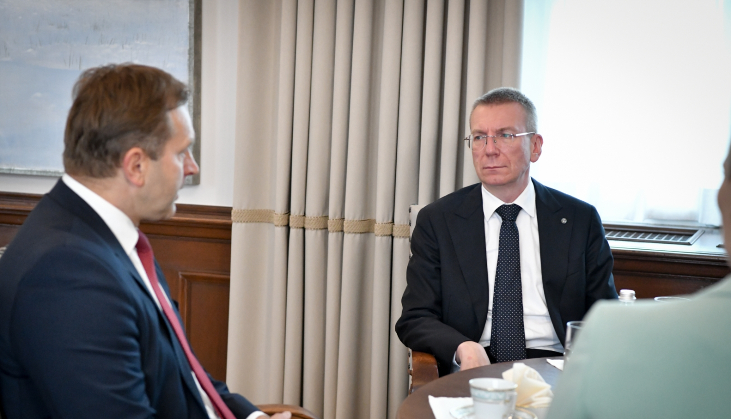 Aldis Laviņš un Edgars Rinkēvičs sēž pie galda un sarunājas