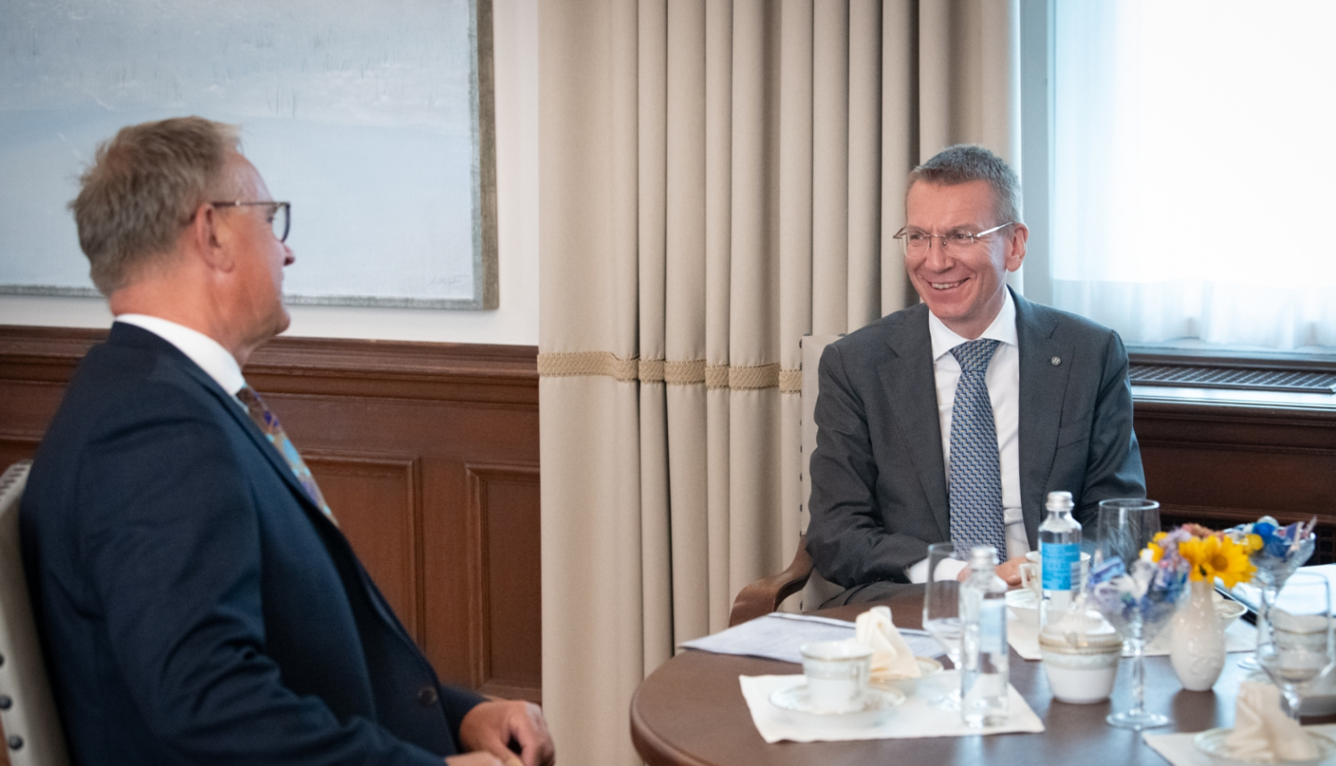 Nauris Puntulis un Edgars Rinkēvičs sēž pie galda un sarunājas