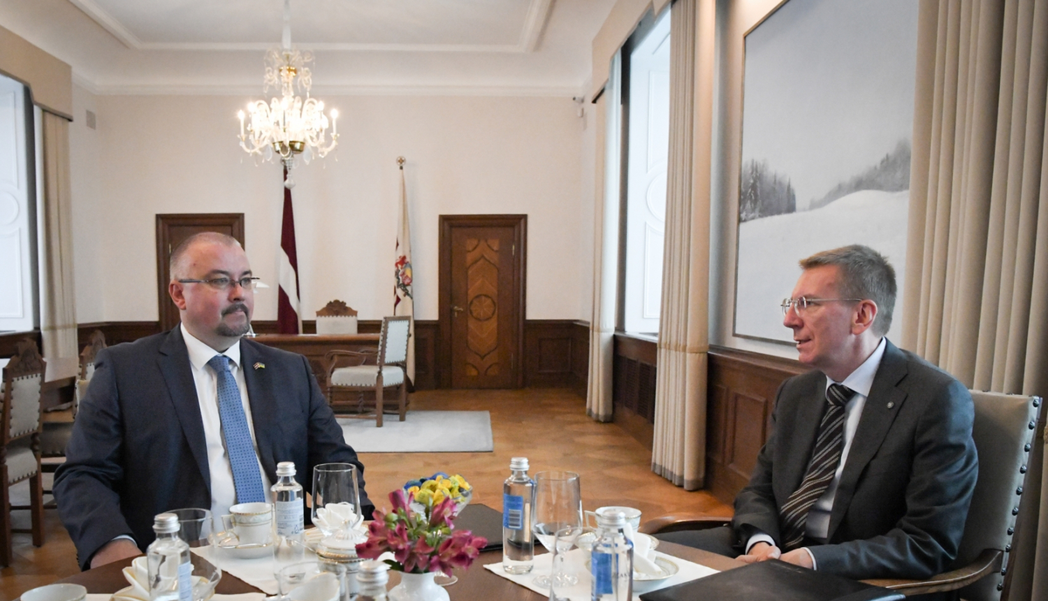 Jēkabs Straume un Edgars Rinkēvičs sēž pie galda un sarunājas